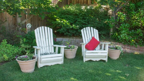 two white chairs and flower pots in the garden